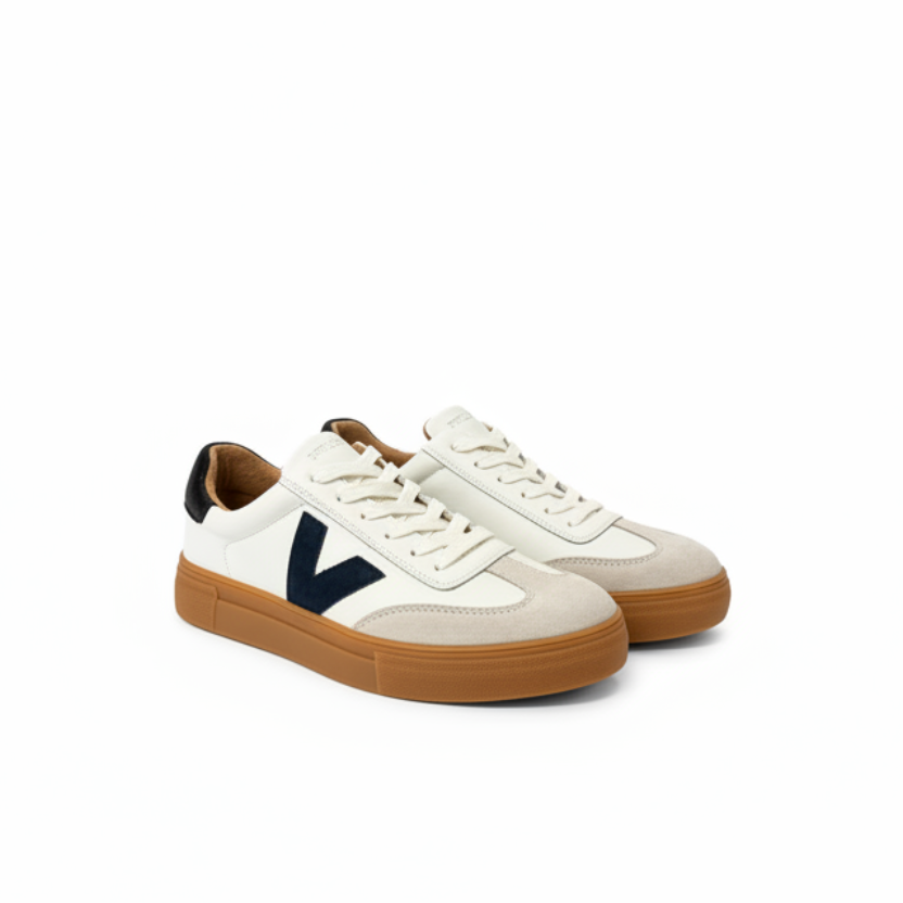 A pair of low-top sneakers in off-white leather and beige suede, featuring a prominent navy blue V logo on the side, cream laces, and a brown gum rubber sole.